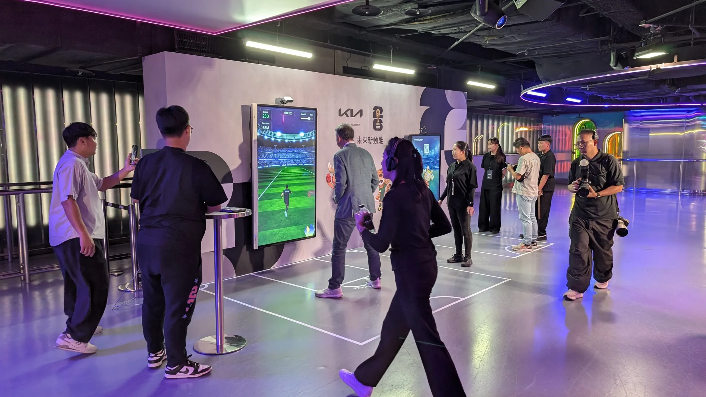 Guests play Kia Move Challenge at the media party while a photographer and other guests look on