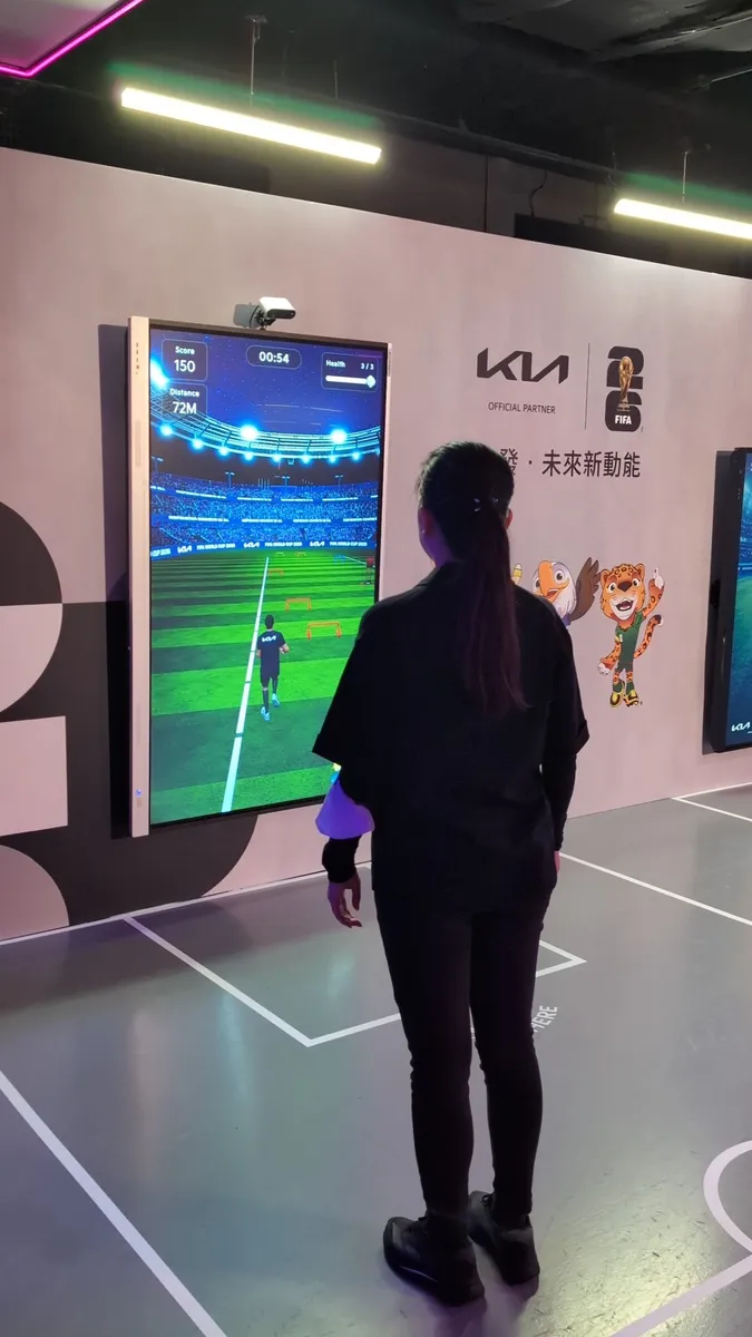 A player stands in front of the screen as the footballer runs up the pitch