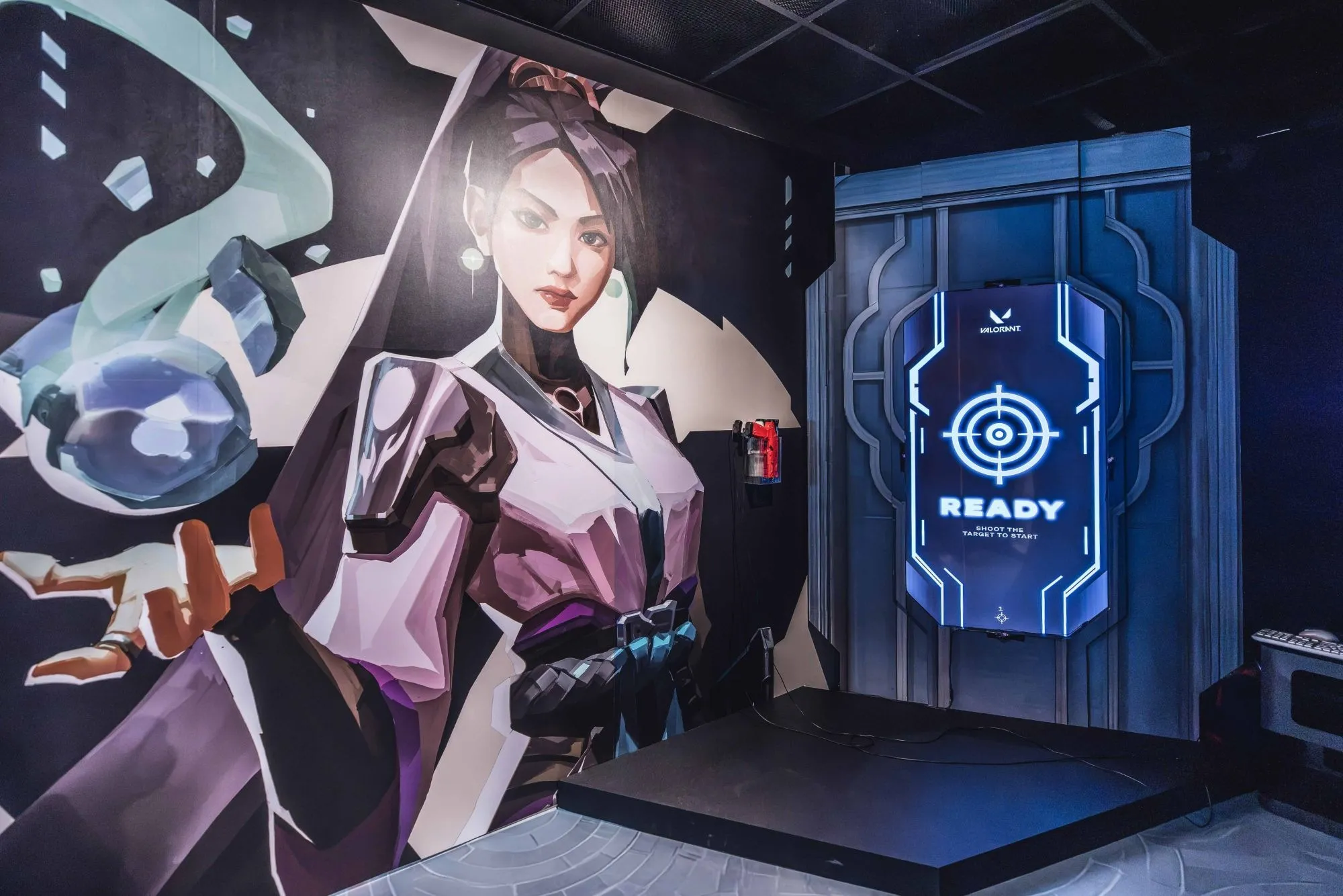 The game screen showing READY, set into the scenic wall beside a mural of a VALORANT agent